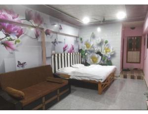 um quarto com uma cama e um sofá e flores na parede em Hotel Dabral, Pipalkoti em Pīpalkoti