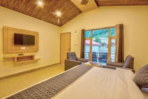 a bedroom with a bed and a tv and a balcony at The Shivalaya Retreat - A River Side Resort in Jagatsukh