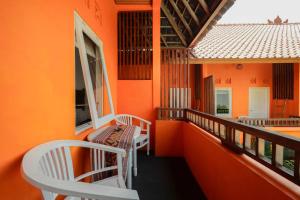 a balcony with orange walls and white chairs at The Room Padang-Padang in Uluwatu