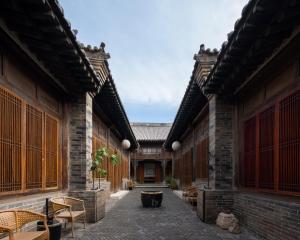 平遥Jing's Residence Pingyao的一座配有桌椅的亚洲建筑的庭院