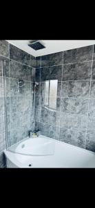 a bathroom with a white tub and a tile wall at Master room in Bristol