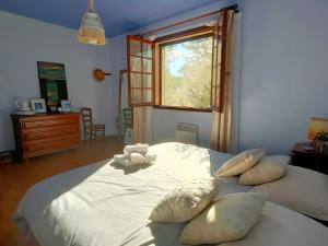 Un dormitorio con una cama blanca con almohadas y una ventana en Villa Les Chariotins, en Draguignan