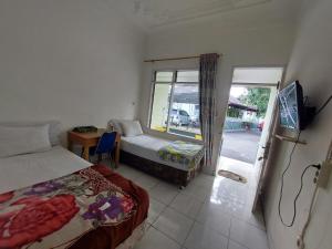 een slaapkamer met 2 bedden en een glazen schuifdeur bij Grand Syariah Guest House Humanitas in Pematangsiantar