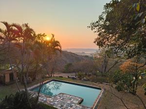 a swimming pool with the sunset in the background at Eloff Guest House and Gallery in White River