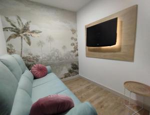 sala de estar con sofá azul y TV de pantalla plana en Ciudad Rodrigo Centro en Ciudad Rodrigo