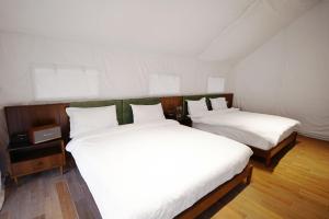 two beds in a room with white sheets at Teela- The Glamping Resort in Udāsar