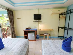 a room with two beds and a desk and a tv at Forever Kohmook Bungalows in Koh Mook