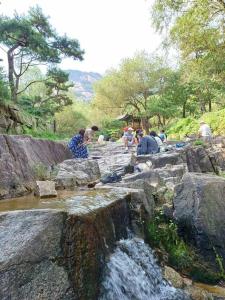 grupa ludzi siedzących na skałach koło wodospadu w obiekcie Seochon Orak Stay w Seulu