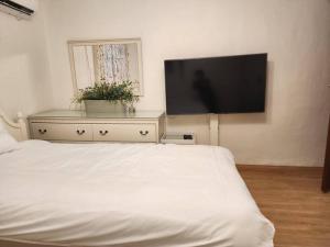 a bedroom with a white bed and a flat screen tv at Seochon Orak Stay in Seoul