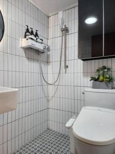 a white tiled bathroom with a toilet and a sink at Seochon Orak Stay in Seoul