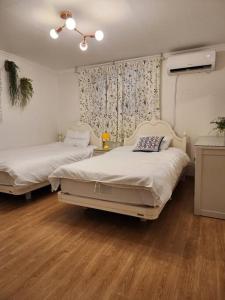 a bedroom with two beds and a window and wooden floors at Seochon Orak Stay in Seoul