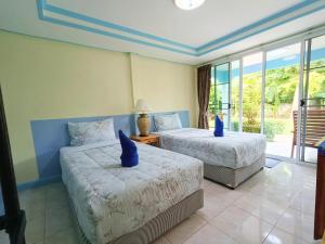 a bedroom with two beds with blue pillows at Forever Kohmook Bungalows in Koh Mook