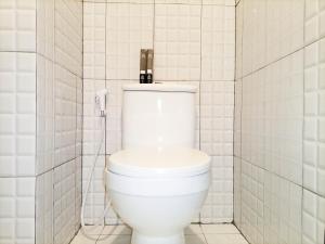 um WC branco numa casa de banho com azulejos brancos em Brand New Studio at De Prima Apartment Medan By Travelio em Medan