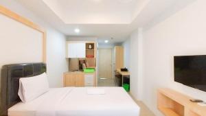 um quarto branco com uma cama e uma televisão em Brand New Studio at De Prima Apartment Medan By Travelio em Medan