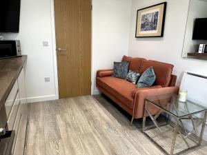 ein Wohnzimmer mit einem braunen Sofa und einem Glastisch in der Unterkunft Cosy 1 Bedroom Apartment In Cardiff in Cardiff