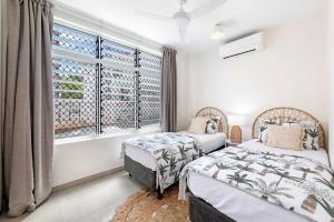 two beds in a room with a window at Botanica Trio - Best Nightcliff Residence for Groups in Nightcliff