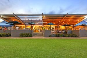 a building with tables and umbrellas on the side at 'The Botanica' A Triple-apartment Residence in Nightcliff in Darwin