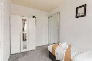 a white bedroom with a bed and a mirror at Stunning 2 bed apartment Free Parking in Edinburgh