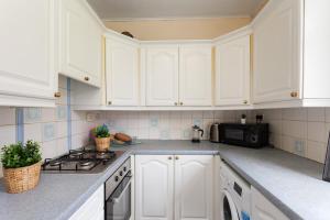 a white kitchen with white cabinets and a microwave at Stunning 2 bed apartment Free Parking in Edinburgh