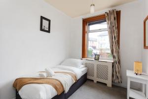 um pequeno quarto com uma cama e uma janela em Stunning 2 bed apartment Free Parking em Edimburgo