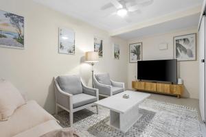 ein Wohnzimmer mit einem Sofa und einem TV in der Unterkunft Holiday on Hedges - Simple Beachside Comforts in Gold Coast