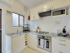 eine weiße Küche mit einer Spüle und einer Mikrowelle in der Unterkunft The Cosy Corner - Your Chic Adelaide Base in Wayville