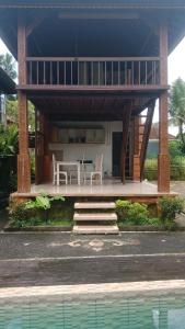 a house with a table and chairs in front of it at Ubud Sawah Scenery Villa and Homestay in Tegalalang