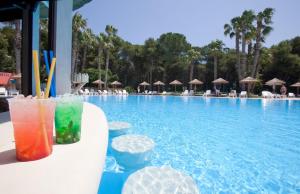 a pool with some drinks on a table next to it at Hotel Solara in Conca Specchiulla
