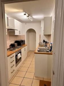 a kitchen with white cabinets and a sink at Charming 2 Bedroom Cottage in Staines Upon Thames in Staines upon Thames
