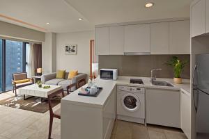 a kitchen with a washing machine and a living room at Novotel Living Saigon South in Ho Chi Minh City