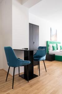 ウィーンにあるCity Stay Vienna – Lugeckの青い椅子2脚、デスク、ベッド1台が備わる客室です。