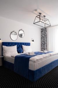 a bedroom with a blue bed with two mirrors on the wall at City Stay Vienna – Lugeck in Vienna