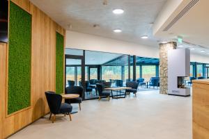 a waiting room with tables and chairs and green walls at Spa & Wellness Hotel Fitak**** in Liptovský Ján