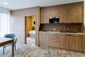 a kitchen with wooden cabinets and a sink and a bed at Spa & Wellness Hotel Fitak**** in Liptovský Ján