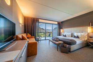 um quarto de hotel com uma cama grande e uma televisão em The Lodge Sporthotel - Golfclub Eppan em Appiano sulla Strada del Vino