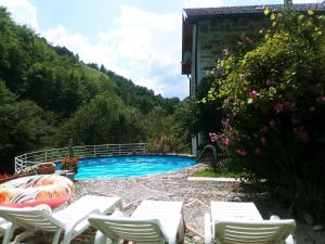 a swimming pool with white chairs next to a building at Pri Maku in Tolmin