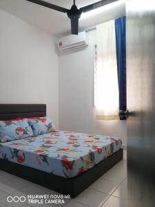 - une chambre avec un lit avec une couette à fleurs et une fenêtre dans l'établissement Jannah Guest House Putrajaya, à Putrajaya