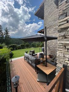 a wooden deck with a couch and an umbrella at Katarino Spa Chalet in Razlog