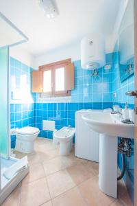- une salle de bains carrelée de bleu avec 2 toilettes et un lavabo dans l'établissement Apartment I Nidi dei Cormorani, à Costa Rei