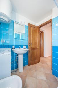 ein blau gefliestes Bad mit einem Waschbecken und einem WC in der Unterkunft Apartment I Nidi dei Cormorani in Costa Rei