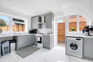 een keuken met witte kasten en een wasmachine en droger bij 3 Bedroom House with Parking in Windsor - Family and Contractor friendly in Windsor