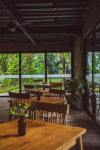 a restaurant with wooden tables and chairs and windows at White Penny Hostel in Seminyak