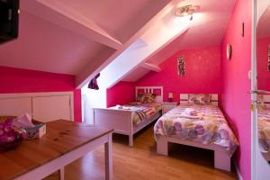 a pink bedroom with two beds and a table at Orval16 in Villers-devant-Orval