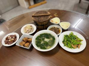 a table with bowls of soup and other food on it at De Ren Tea Gardens in Meishan