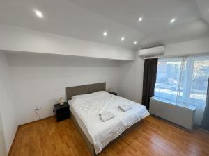 1 dormitorio con 1 cama con sábanas blancas y ventana en Mikasa en Niš