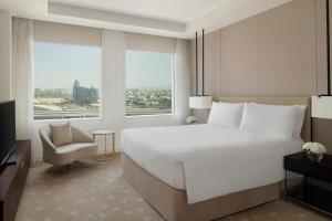 um quarto com uma grande cama branca e uma cadeira em InterContinental Dubai Festival City, an IHG Hotel no Dubai