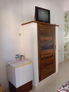 Double N Guesthouse Sanur Bali في سانور: غرفة مع تلفزيون فوق خزانة خشبية