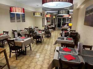une salle à manger avec des tables, des chaises et des serviettes rouges dans l'établissement Logis Hôtel La Bastide d'Entraigues, à Entraigues-sur-la-Sorgue