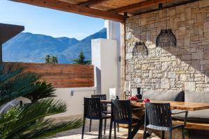 eine Terrasse mit Tisch und Stühlen und einer Steinmauer in der Unterkunft Solis Villa, with Heated Pool & 5 minutes to Beach, By ThinkVilla in Kavros