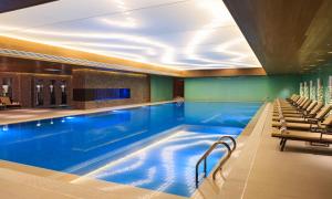 uma grande piscina num hotel com cadeiras em Renaissance Beijing Wangfujing Hotel em Pequim